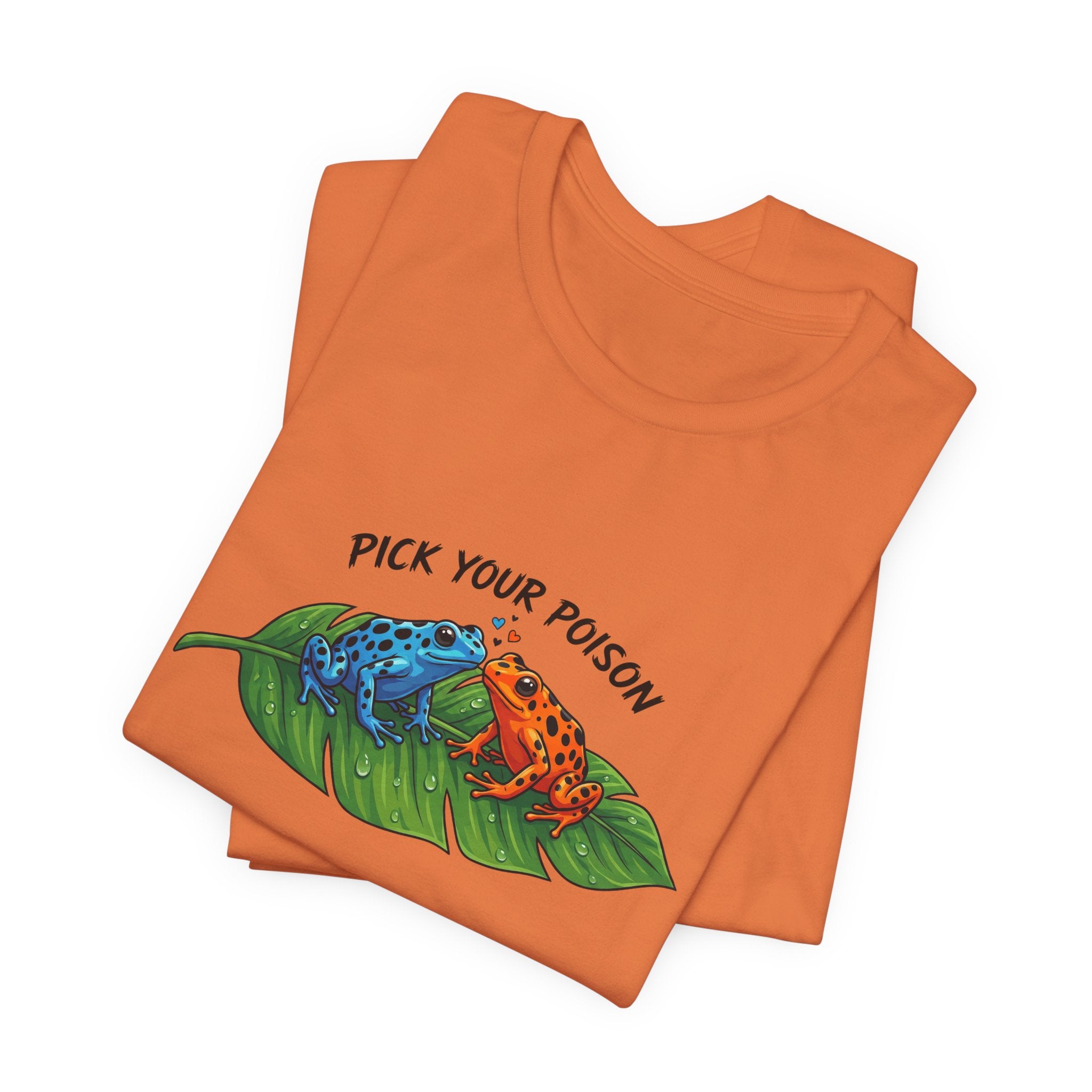 Folded orange t-shirt with a graphic of two poison dart frogs on a leaf and 'Pick Your Poison' text by Soon To Be Mythical