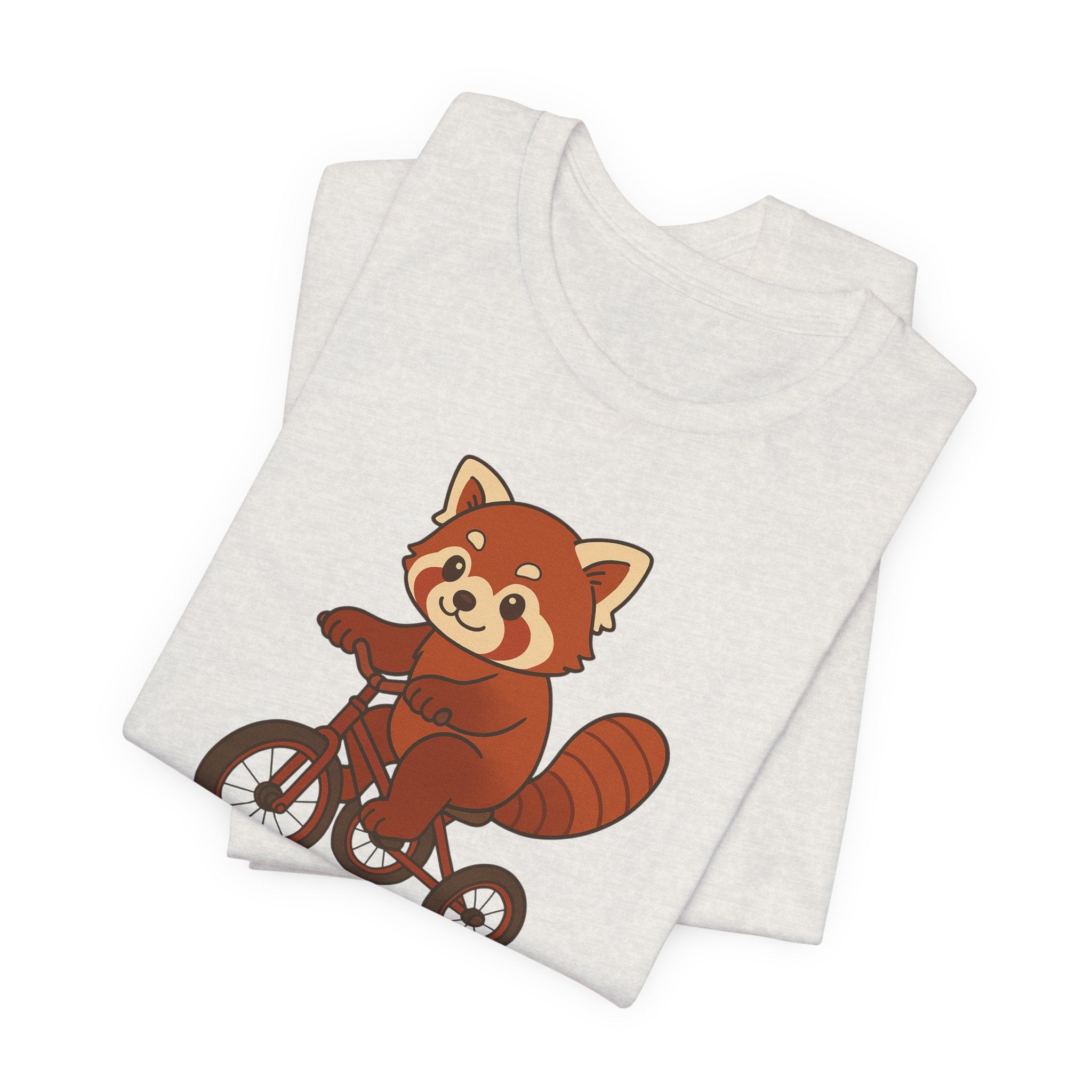 Folded heather cement t-shirt with a red panda riding a tricycle graphic on a white background