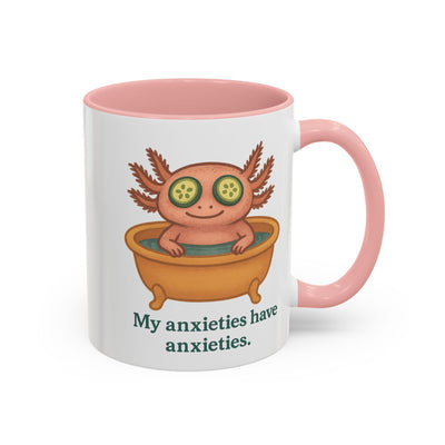 White mug with pink interior and handle color accent featuring a graphic of a cute axolotl taking a relaxing bath with the text "My anxieties have anxieties." by Soon To Be Mythical