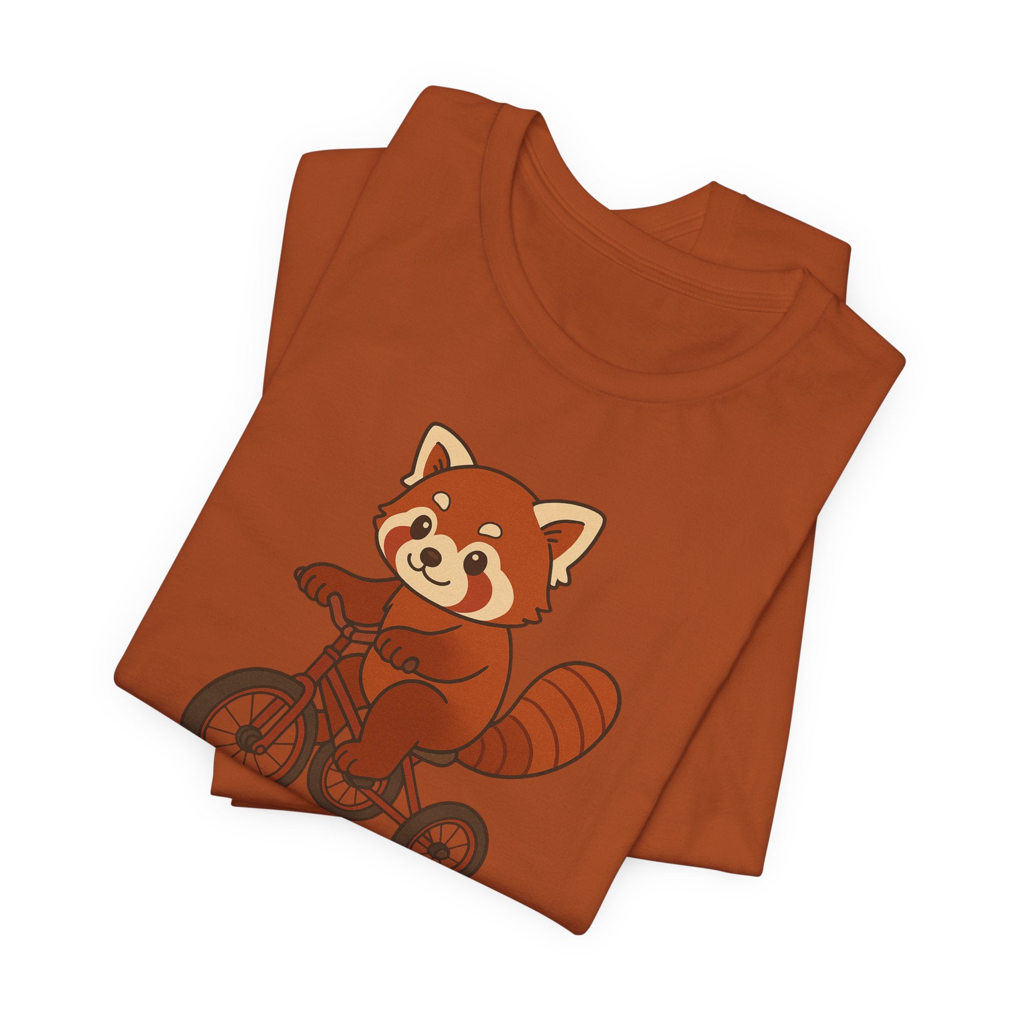 Folded autumn t-shirt with a red panda riding a tricycle graphic on a white background