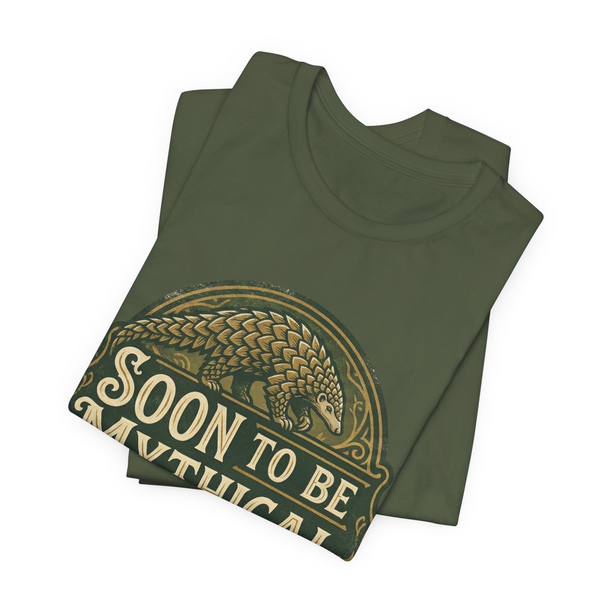 Folded green t-shirt with 'Soon to be Mythical' vintage logo with a pangolin on a white background