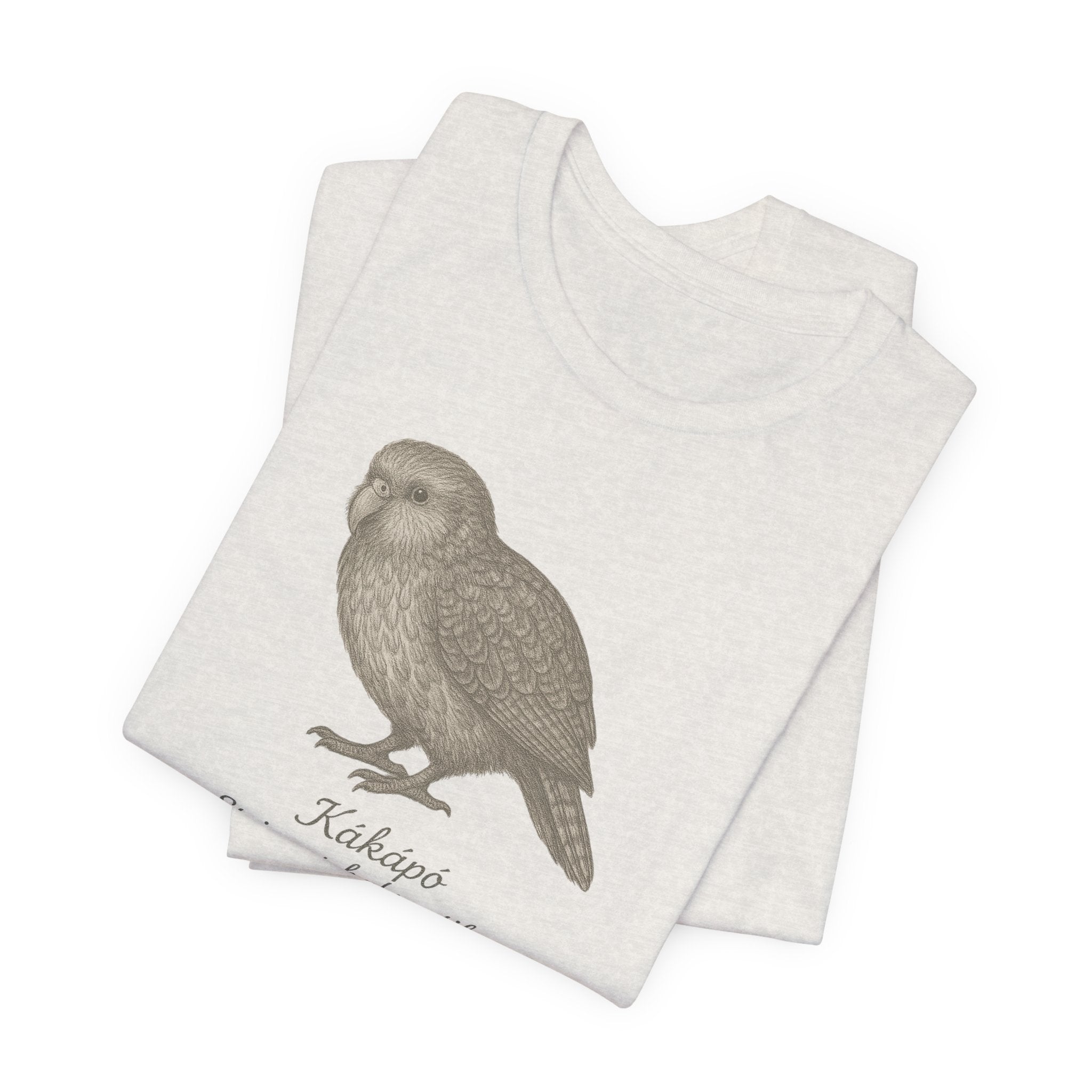 Heather cement t-shirt with a kakapo bird graphic and text of its scientific name on a white background