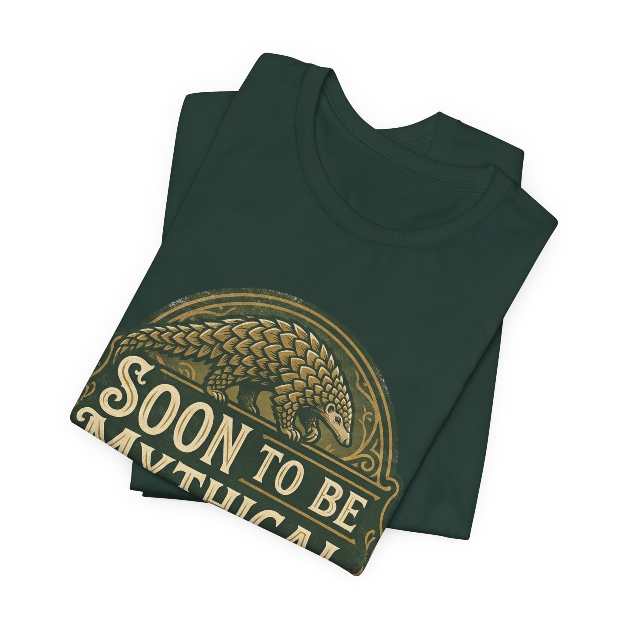 Folded green t-shirt with 'Soon to be Mythical' vintage logo with a pangolin on a white background