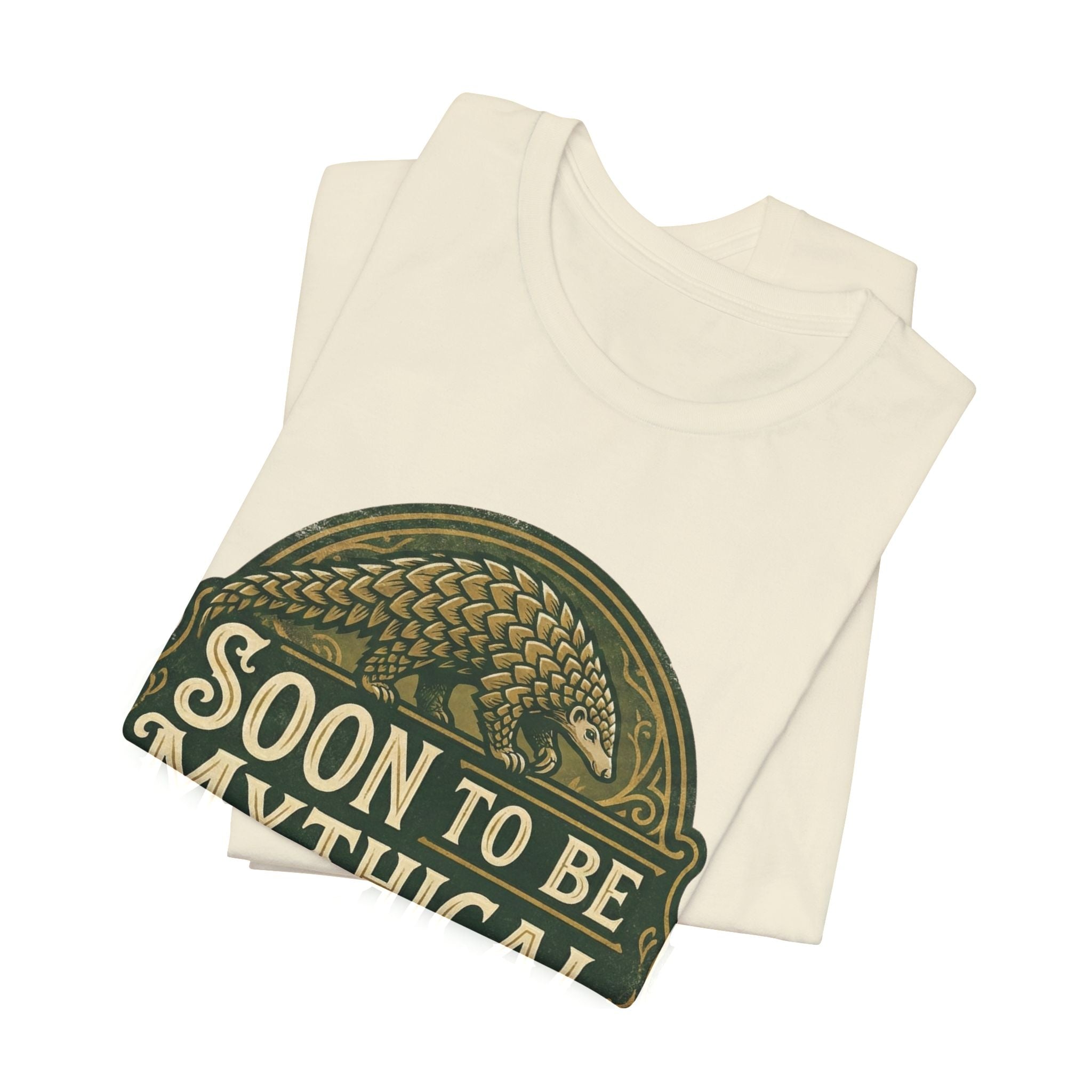 Folded heather beige t-shirt with 'Soon to be Mythical' vintage logo with a pangolin on a white background