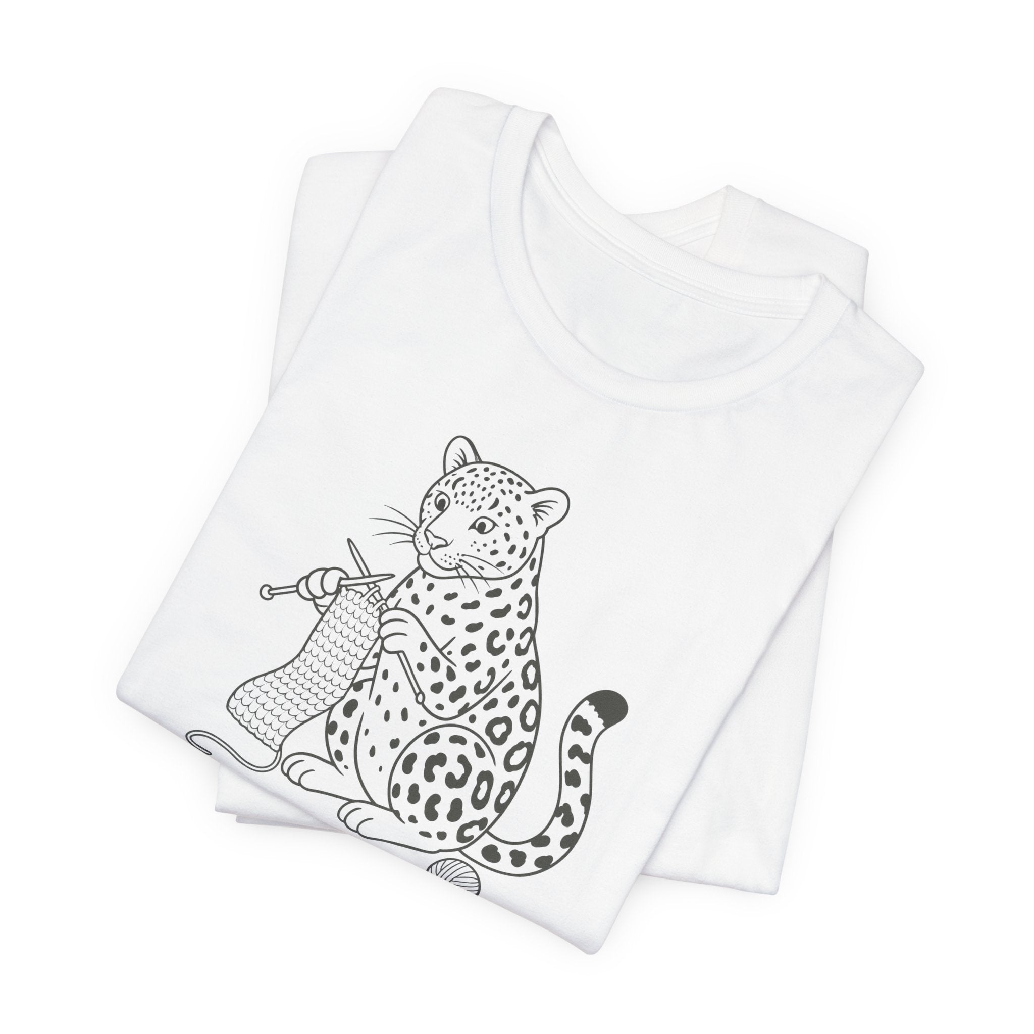 Folded white t-shirt with a black and white illustration of a leopard knitting a scarf on a white background