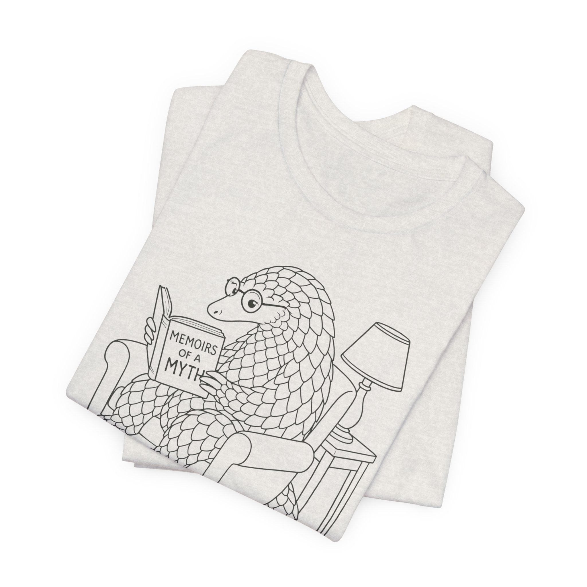 Folded heathered cement t-shirt with a graphic design of a pangolin reading 'Memoirs of a Myth' on a white background